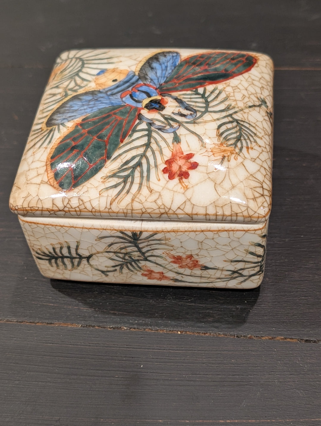 Side view of HomArt porcelain box with hand-painted palm fronds and orange flowers on crackled ivory glaze