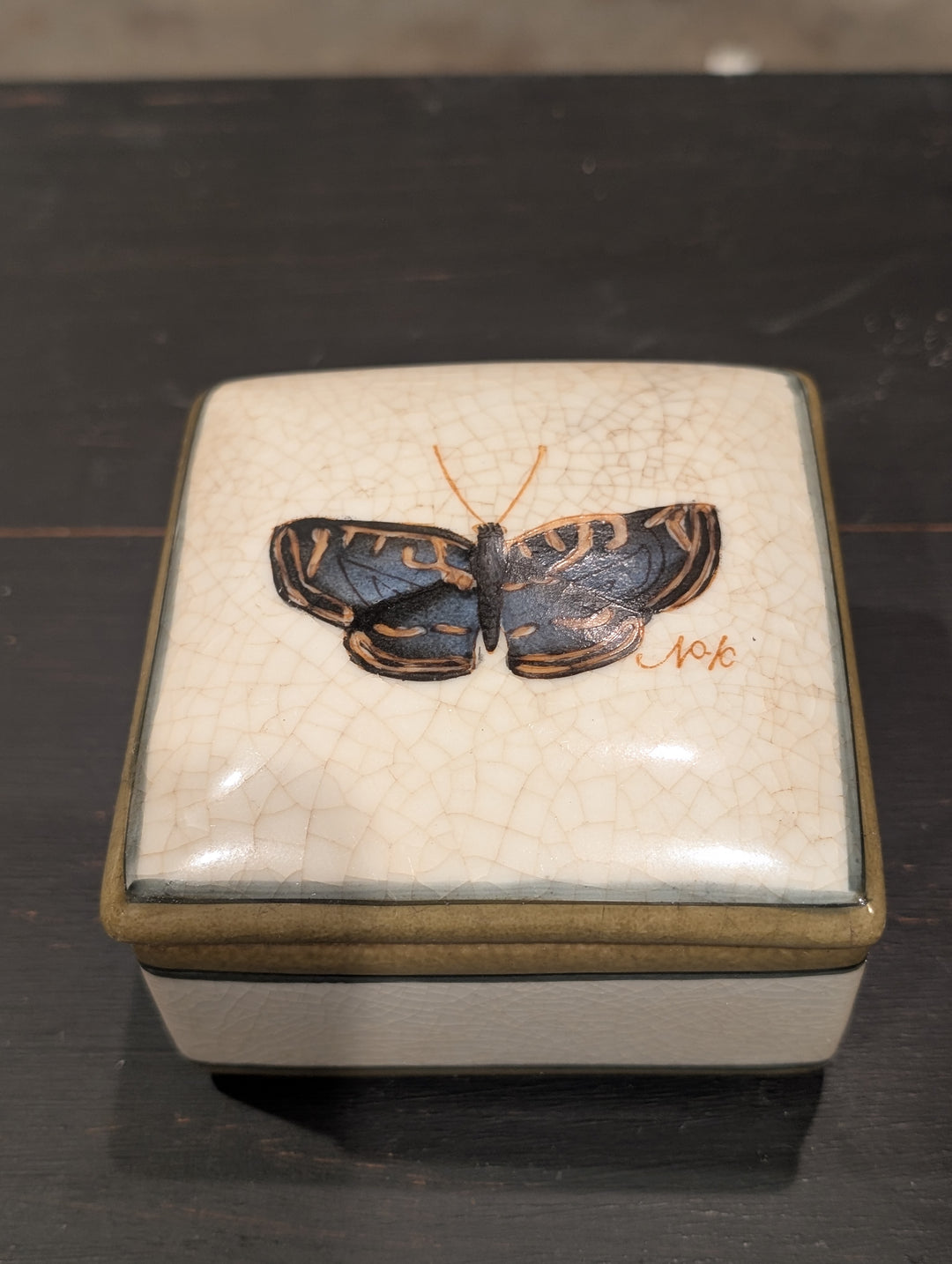 Top view of HomArt porcelain box lid with blue-black butterfly marked No. 6 on crackled ivory glaze