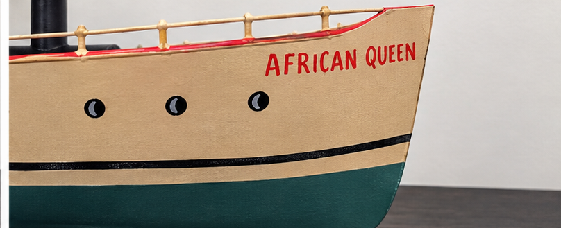 Close-up of African Queen model bow with red lettering and hand-painted portholes