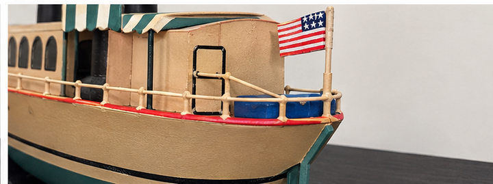 Close-up of African Queen model boat stern showing cabin door, railing, and American flag