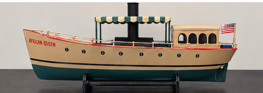 African Queen steamboat model with striped canopy, black funnel, cabin, and American flag on display stand